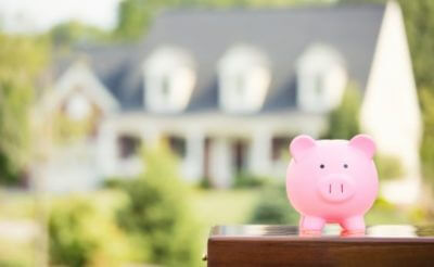 Pink piggybank and a blurred image of a home